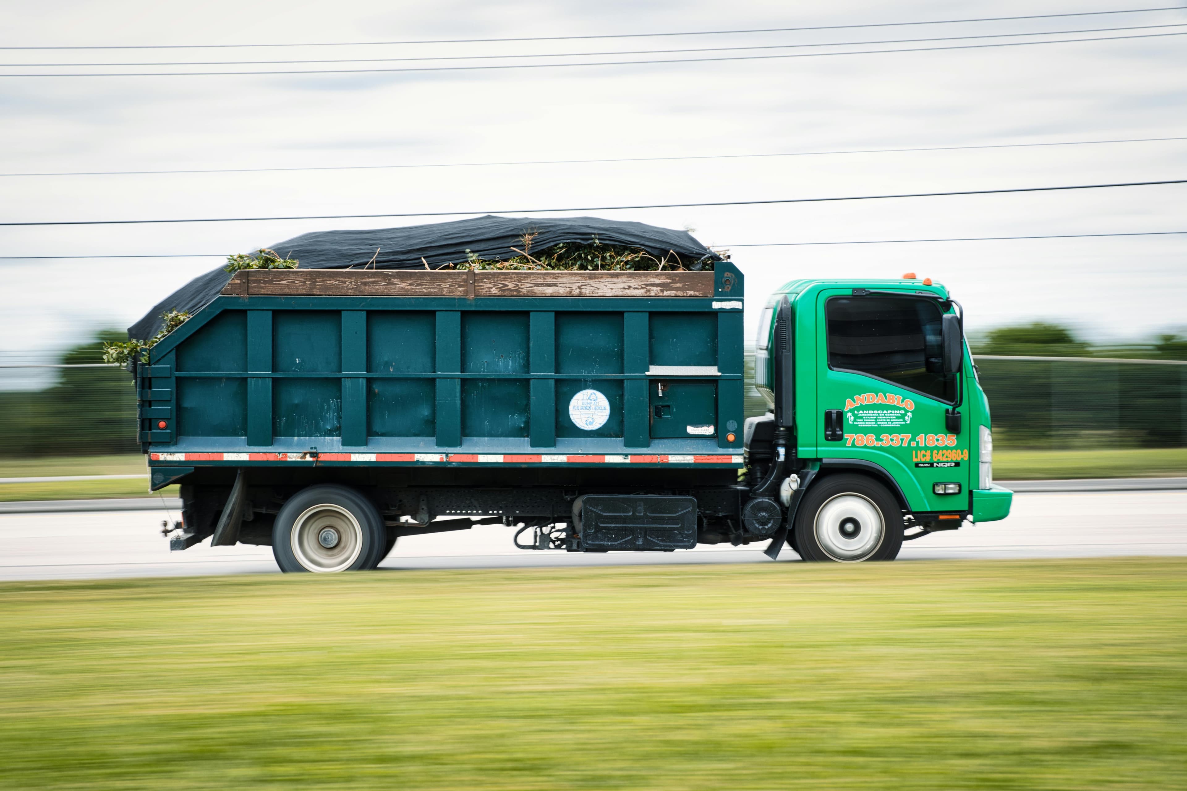 Local junk hauling truck loaded with yard waste and household debris